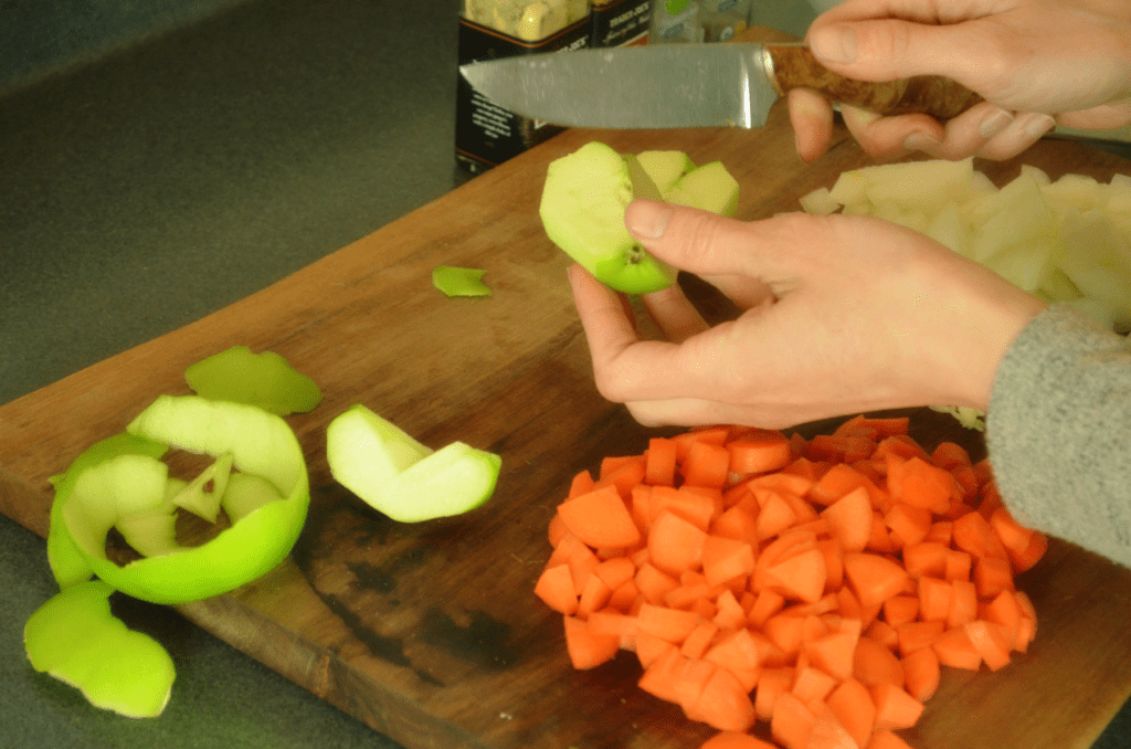 hand cutting apple on cutting board