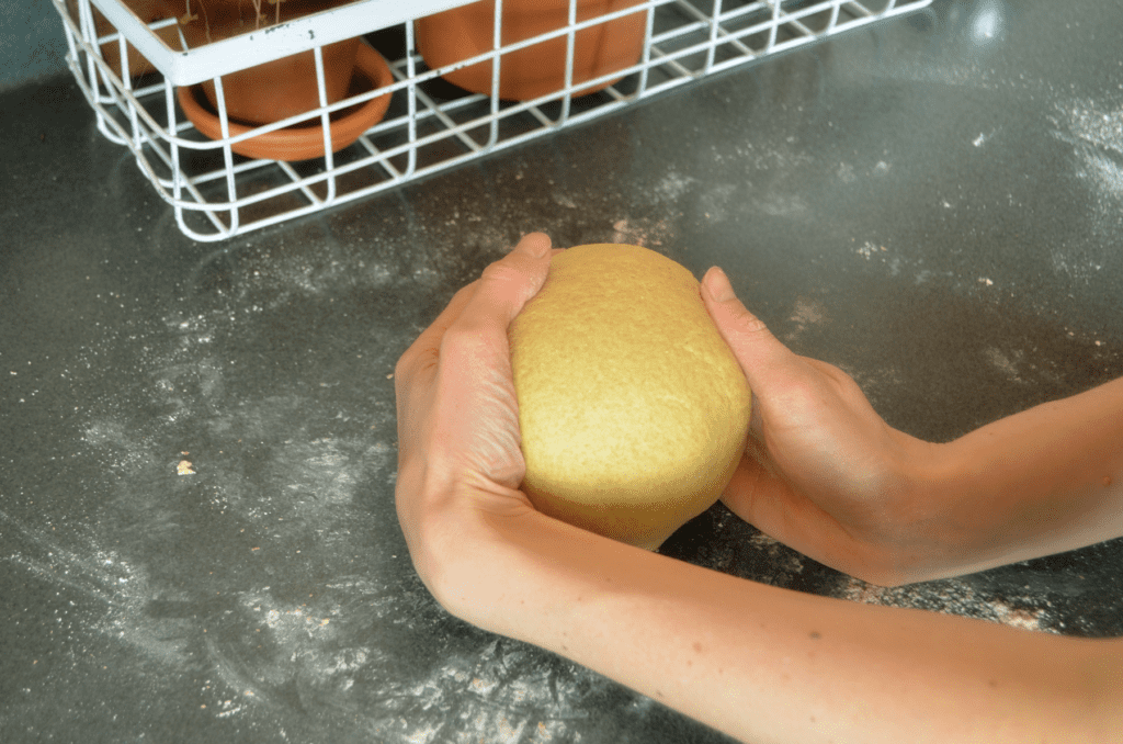 Hands roll dough into ball