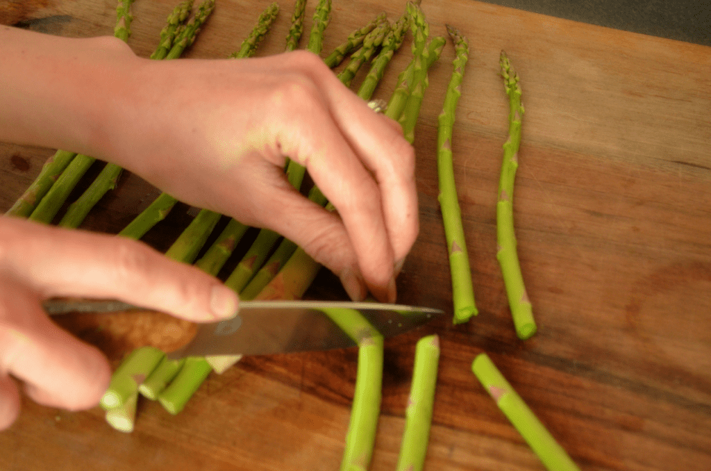 hand cutting ends off green asparagus