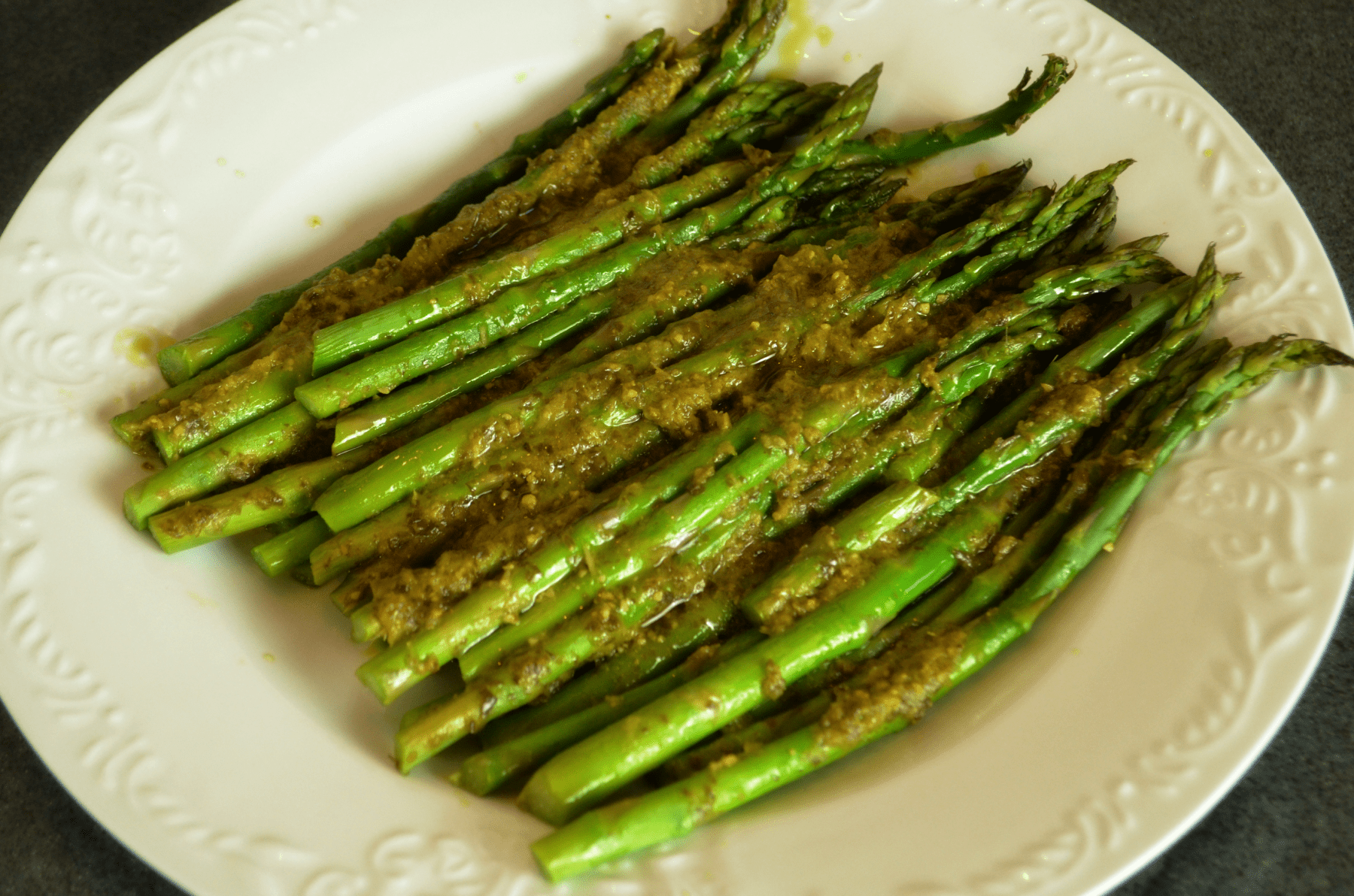 pesto covered asparagus on white serving platter