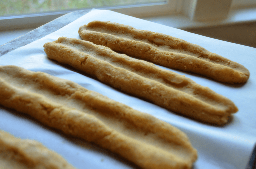 uncooked dough logs with indents down the middle awaiting jam.