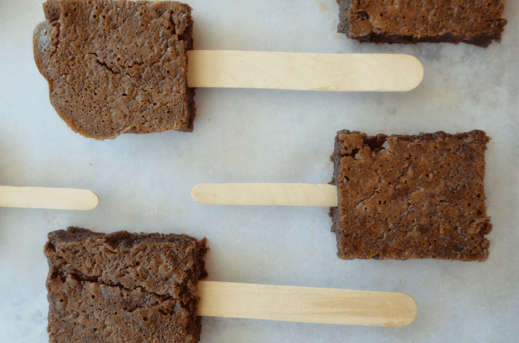 brownies on popsicle sticks lined up on a baking sheet