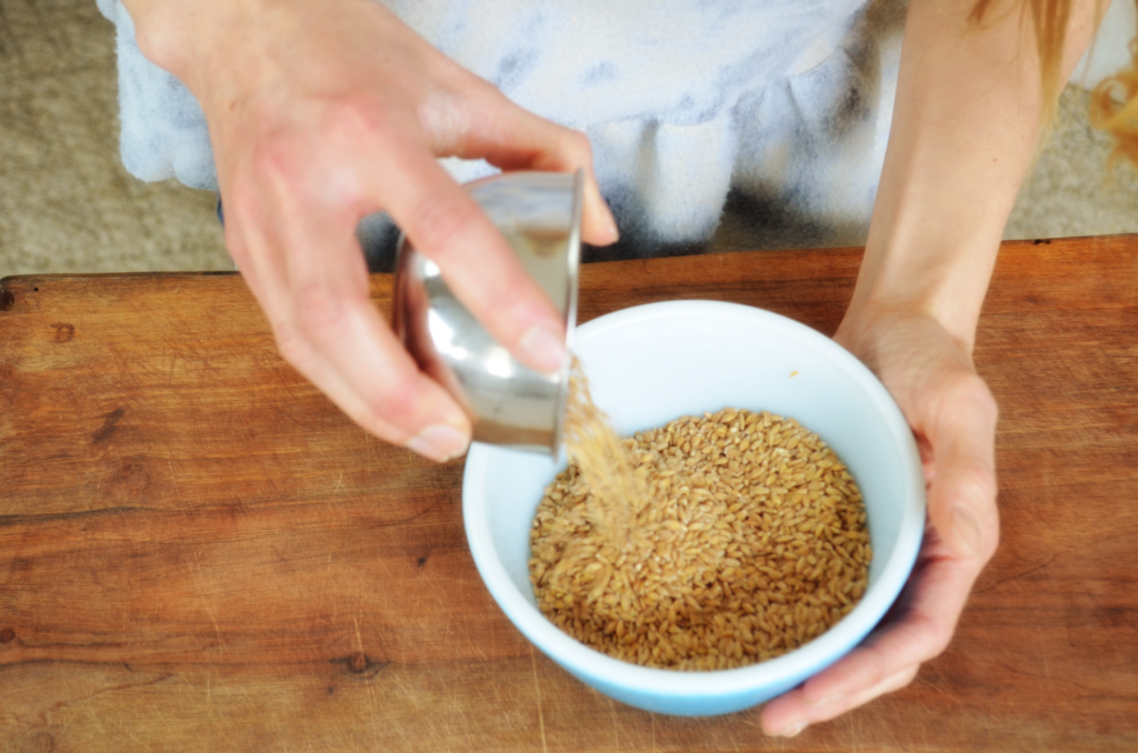 the ancient grain einkorn, is poured into a bowl. The einkorn berries are small but hold tremendous nutritional and anti-inflammatory benefits. 