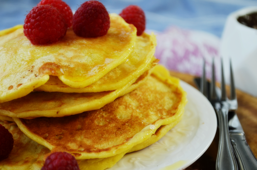 Fluffy Buttermilk einkorn pancakes sit topped with fresh raspberries and dripping butter.