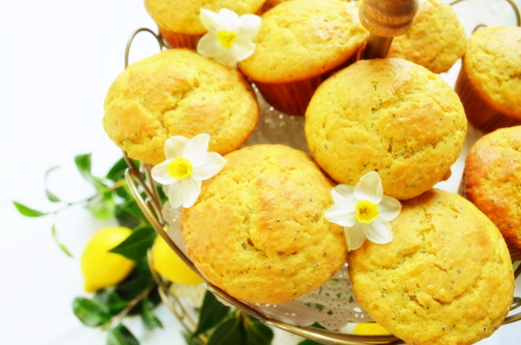 Little white and yellow flowers sit in between the Einkorn Lemon Poppy Seed Muffins