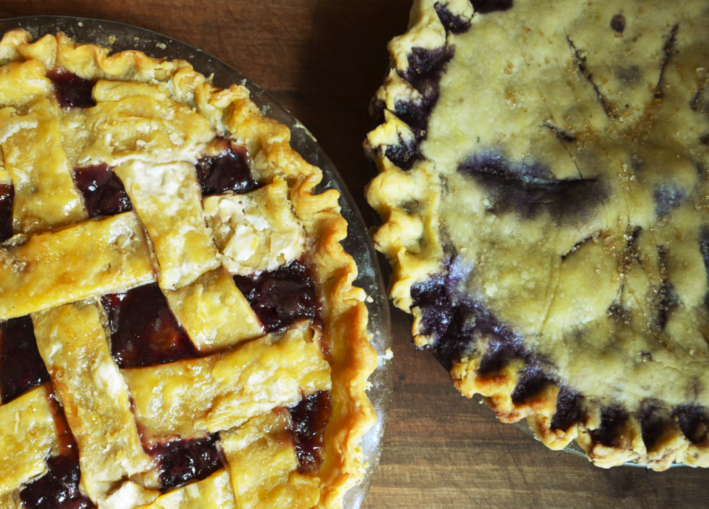 easy blueberry pie homemade with a gluten free crust, next to a cherry pie with a flaky einkorn crust