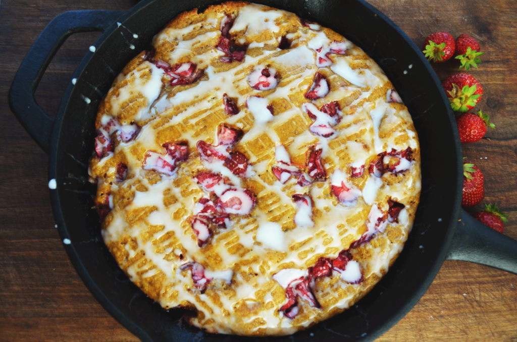 Strawberry Scones with Einkorn flour sit finished on a wooden cutting board with white sweet glaze.