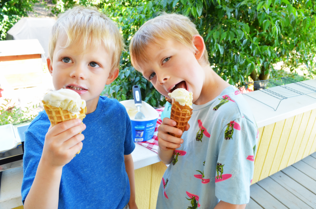 two boys lick ice cream cones freshly made from the pizzelle press. 