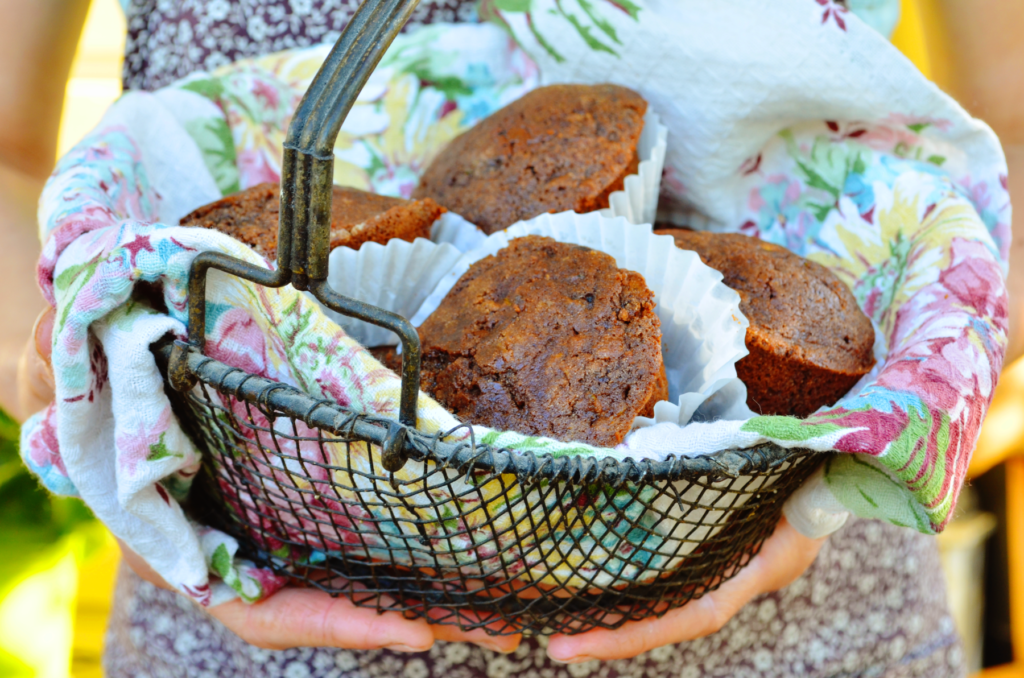 moist gluten free zucchini muffins with salted dark chocolate are held in a basket hot, fresh and ready to be enjoyed.