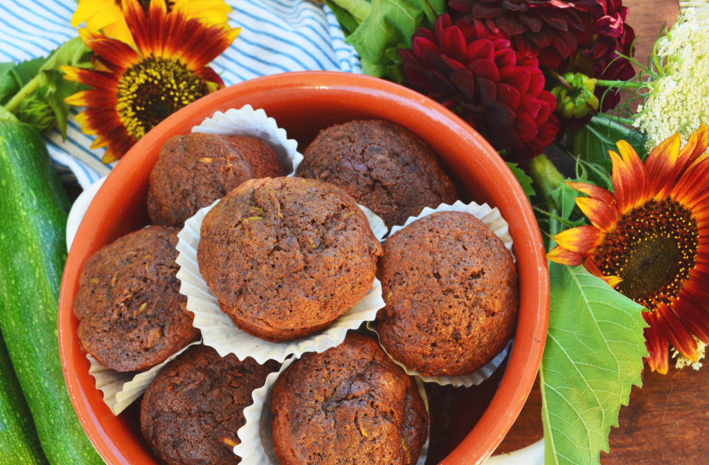 Zucchini Einkorn Muffins with Salted Dark Chocolate sit at a table, ready to share.