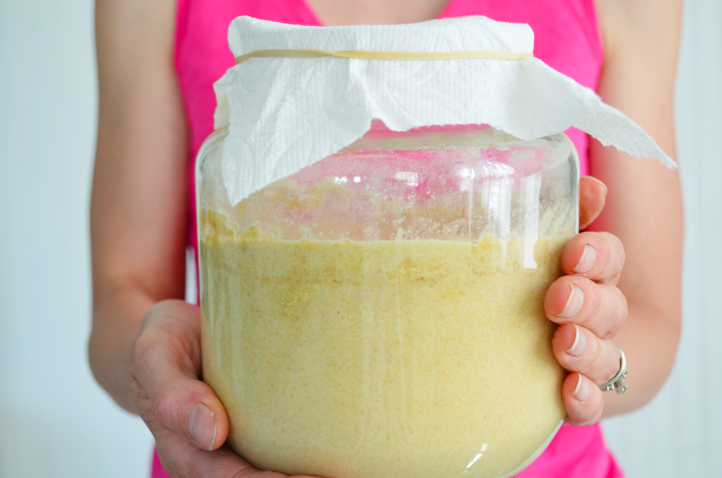 hands carry a large jar with einkorn in sourdough starter