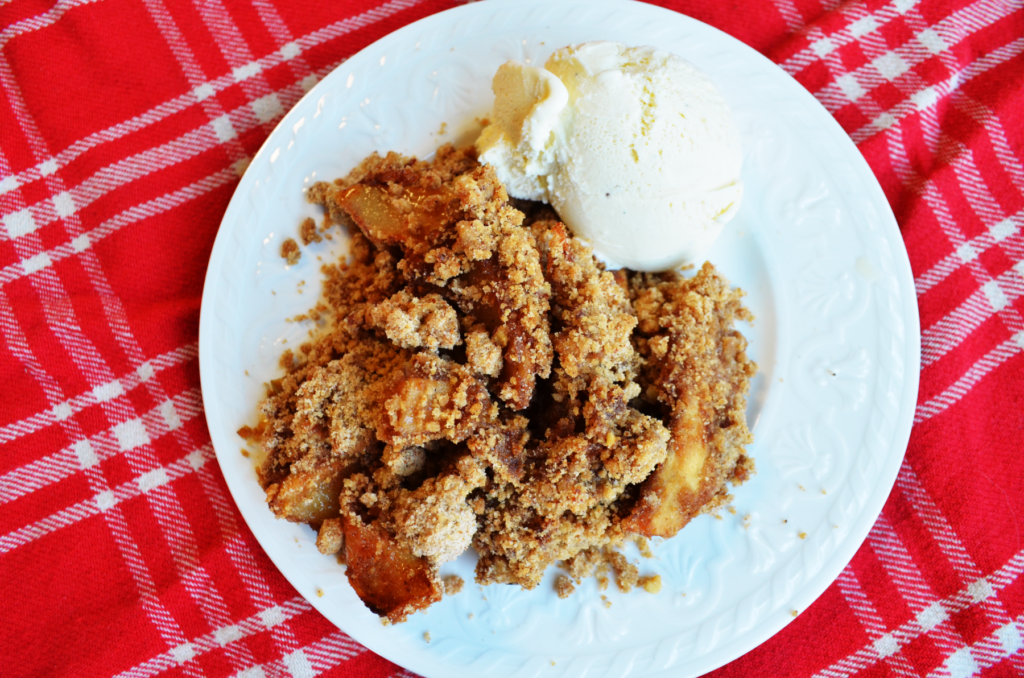 Gluten free apple crisp recipe without oats is served on a white plate with vanilla ice cream