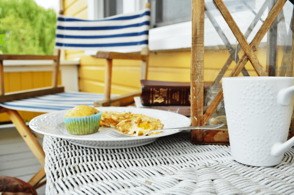 A white wicker table sits on a summer porch with fresh eggs and a muffin. A white mug sits nearby with a large Bible  for studying. Today, the verses are about overwhelming stress.