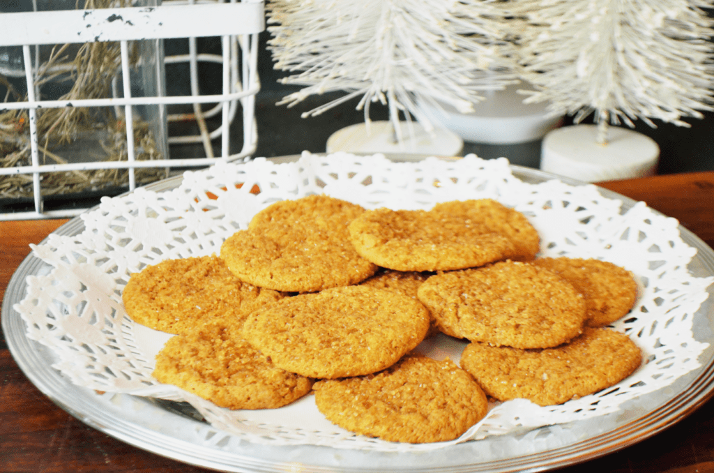 A shiny platter holds a stack of freshly baked chewy gingerbread cookies. The sugary tops of each cookies sparkles in the light.