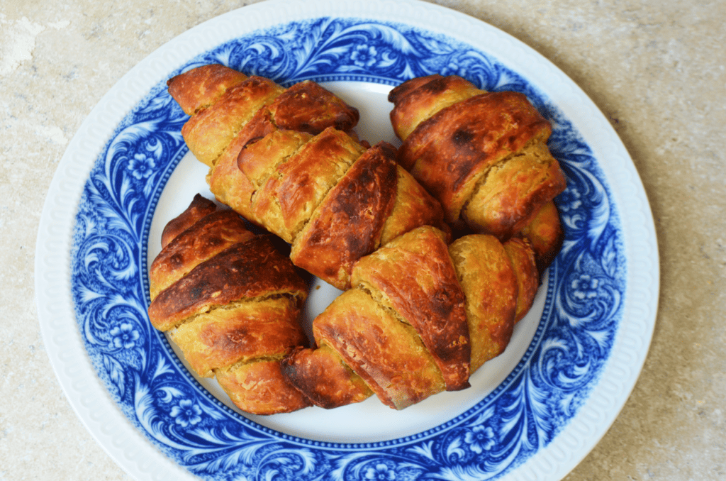 Einkorn Croissants with browned flaky edges cuddle on a elegant flowered plate.