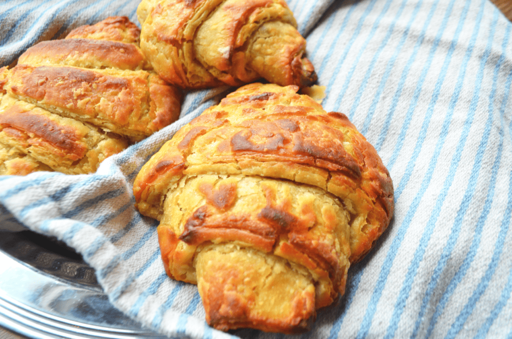 Buttery flaky croissants sit atop a striped blue and white linen towel.