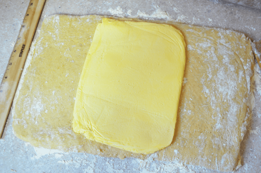 rolled flat butter sits in the middle of dough, ready to be tucked inside the dough before laminating it for croissants.
