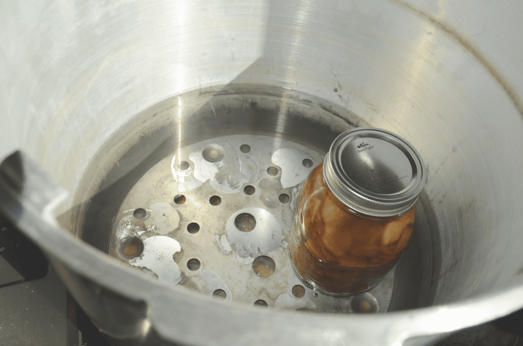 A lone jar awaits others to join it in the bottom of a large canning pot