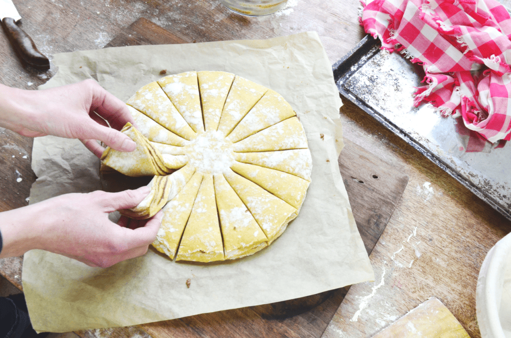 Hands begin to twist two sections of streusel filled dough to make a snowflake bread