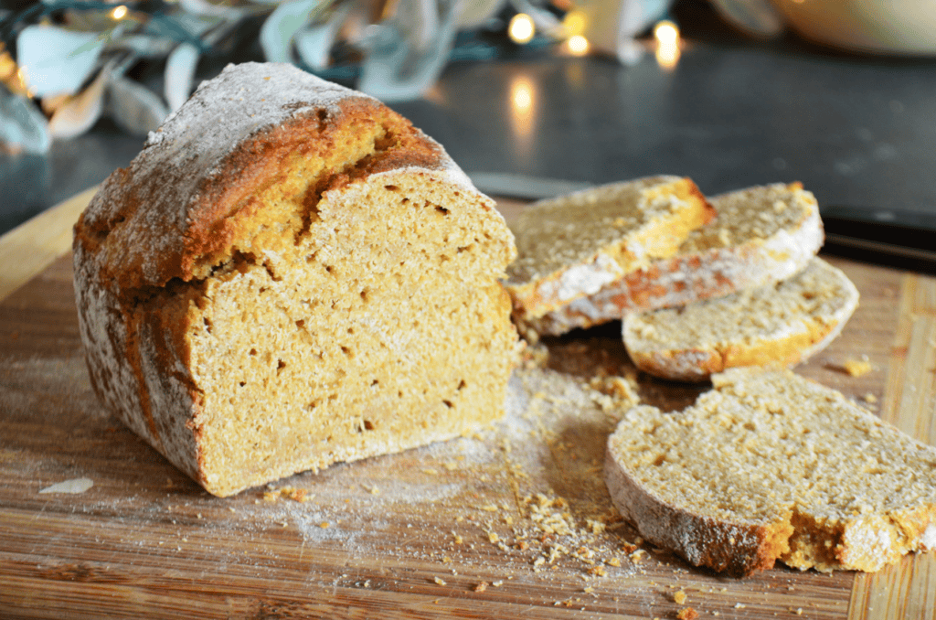 A loaf of Whole grain einkorn bread made with fresh milled flour sits on a cutting board, freshly sliced.