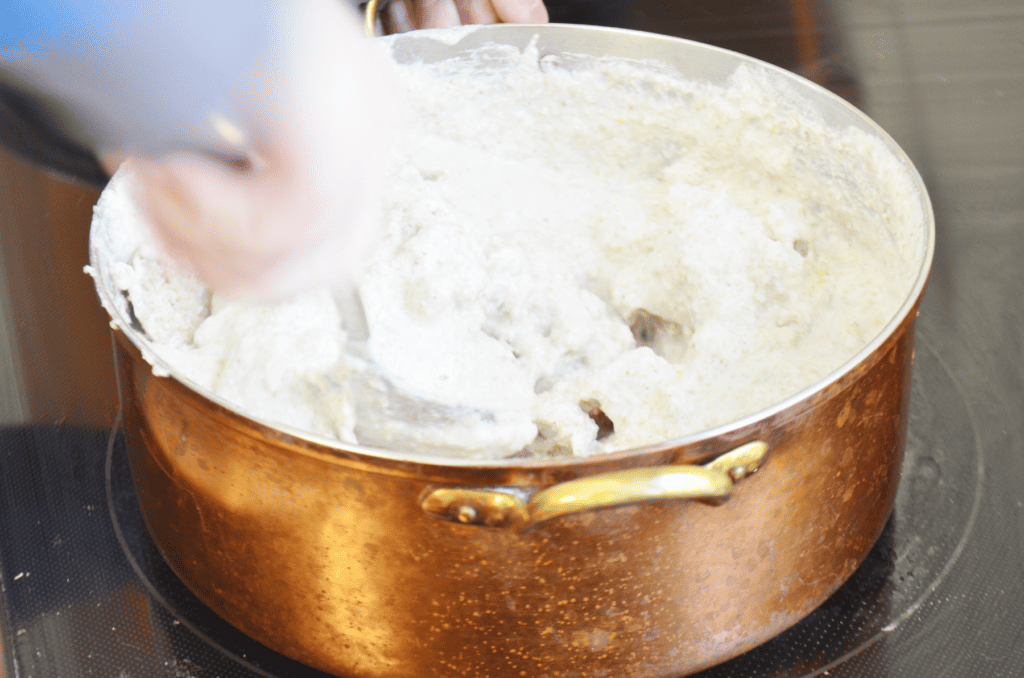 hand stirs cream of buckwheat as it cooks on the stove.