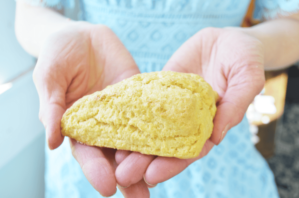 hands hold a fluffy cream scone for tea time