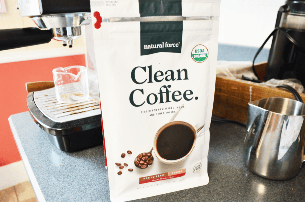 A Natural Force Coffee Bag sits opened in front of an espresso machine