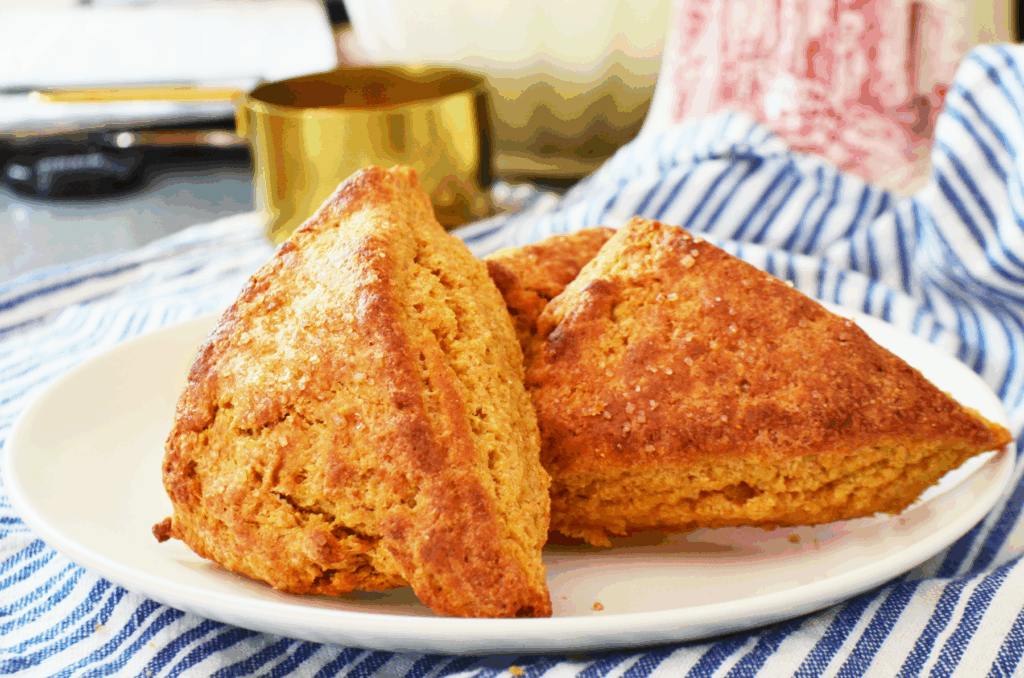 Golden brown scones cool on a bright white plate with sparkling sugar on top of their freshly baked tops.