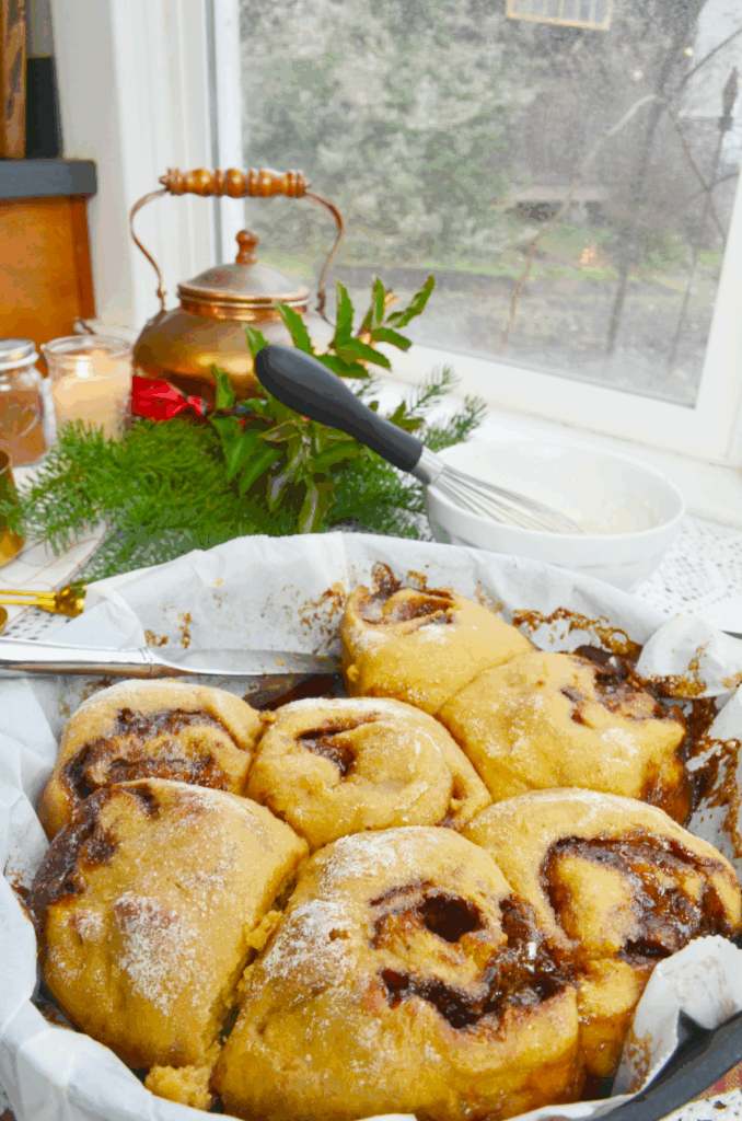 Einkorn sourdough cinnamon rolls in a pan, baked with a dusting of flour on the top.
