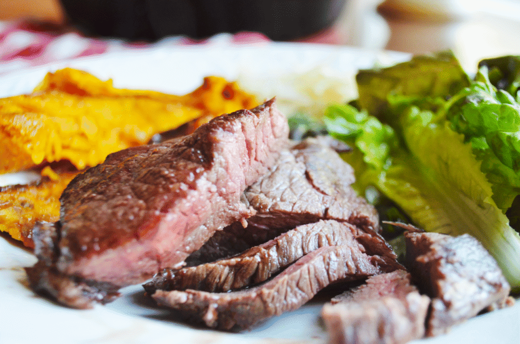 baked steak on a plate being served with lettuce