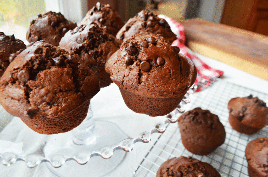 double chocolate sourdough muffins with Einkorn baked, and on a glass cake platter next to a red checkered napkin