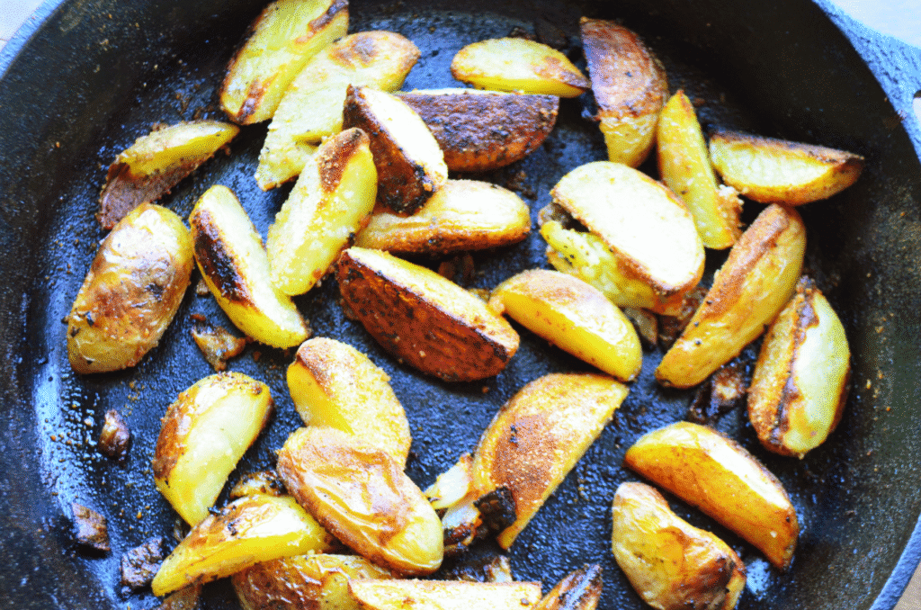 Cooked pieces of potato wedges in a cast iron skillet in the oven